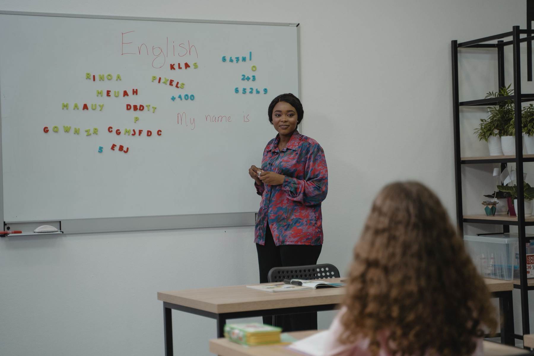 A teacher standing at a whiteboard with the word English written on it