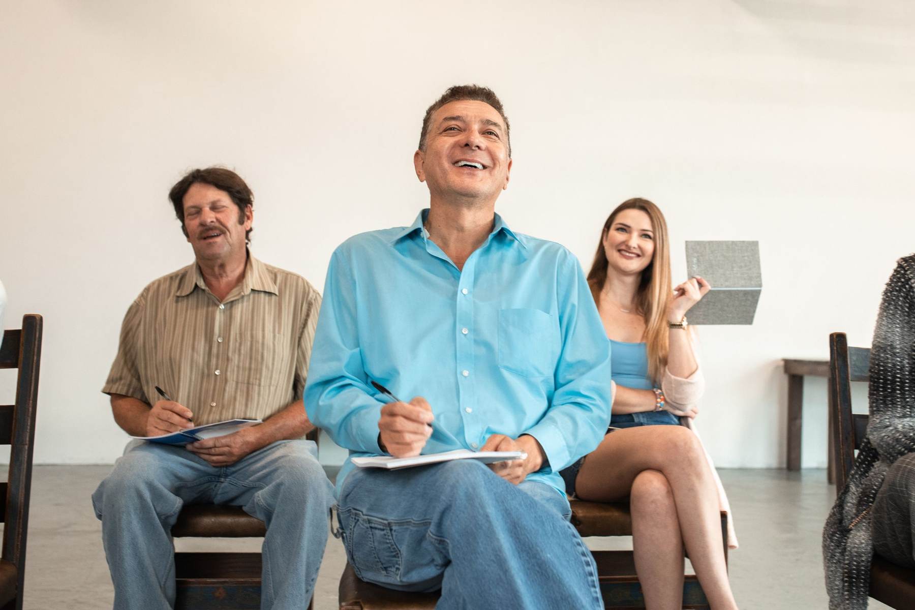 Adult learners smiling and taking notes during a class