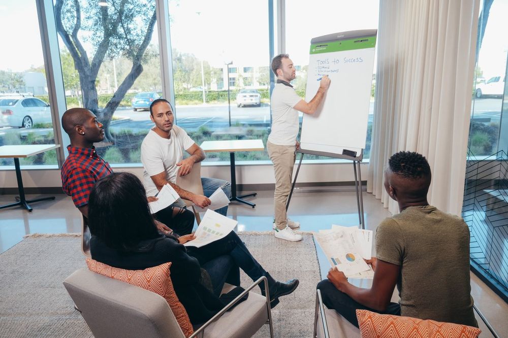 Adult learners in a group session with a facilitator at a flip chart